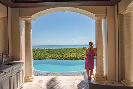 Orchid Island Oceanfront Estates woman looking out at the water and her pool