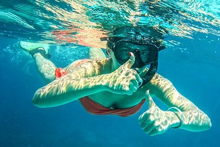 Things to Do in Vero Beach, FL Woman underwater snorkeling, giving a thumbs up to the camera in Vero Beach, FL